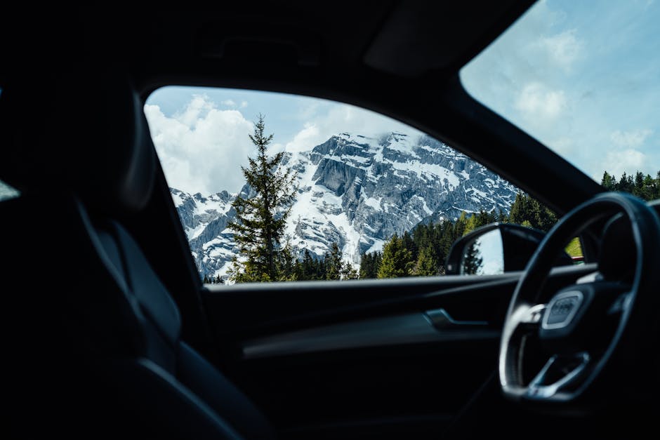 Interior car view showcasing a stunning snowy mountain landscape through the window.